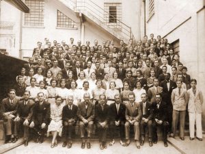 Fotografia antiga mostrando Tranquillo Giannini (sentado na primeira fila da imagem) acompanhado por sua equipe da fábrica de instrumentos Giannini.