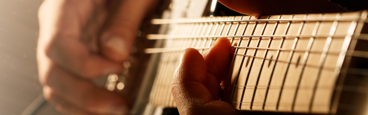 Imagem ilustrativa das mãos de um guitarrista tocando seu instrumento