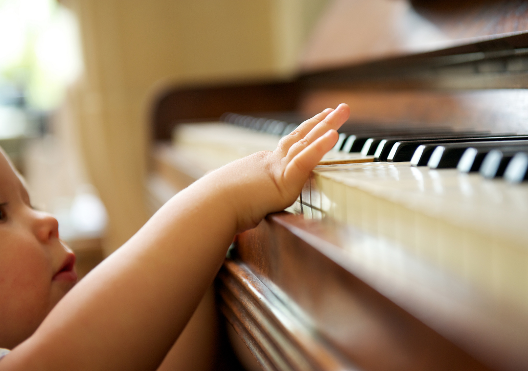 Imagem ilustrativa de uma criança tentando alcançar as teclas do piano com o dedo